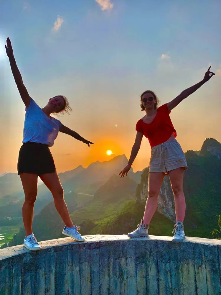 Two travelers watching sunset over karst peaks